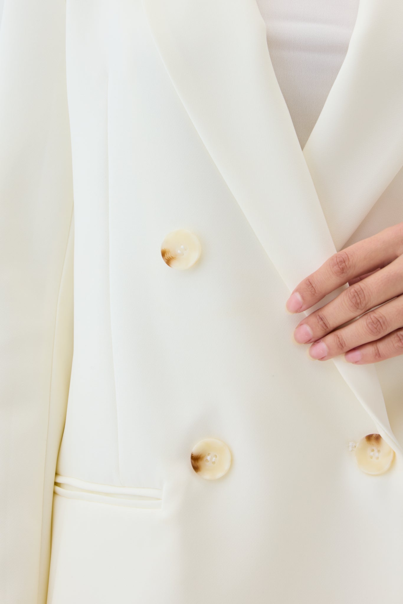 Close-up of a cream-colored blazer with shell buttons