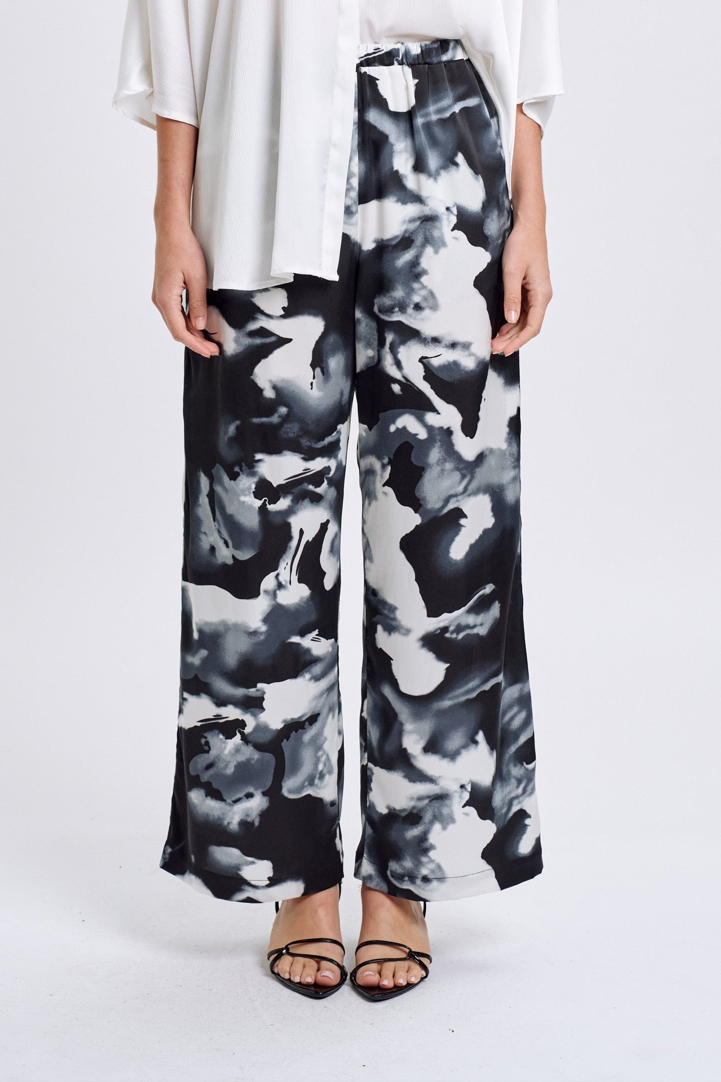 Woman wearing a white shirt and black and white patterned pants on a white background