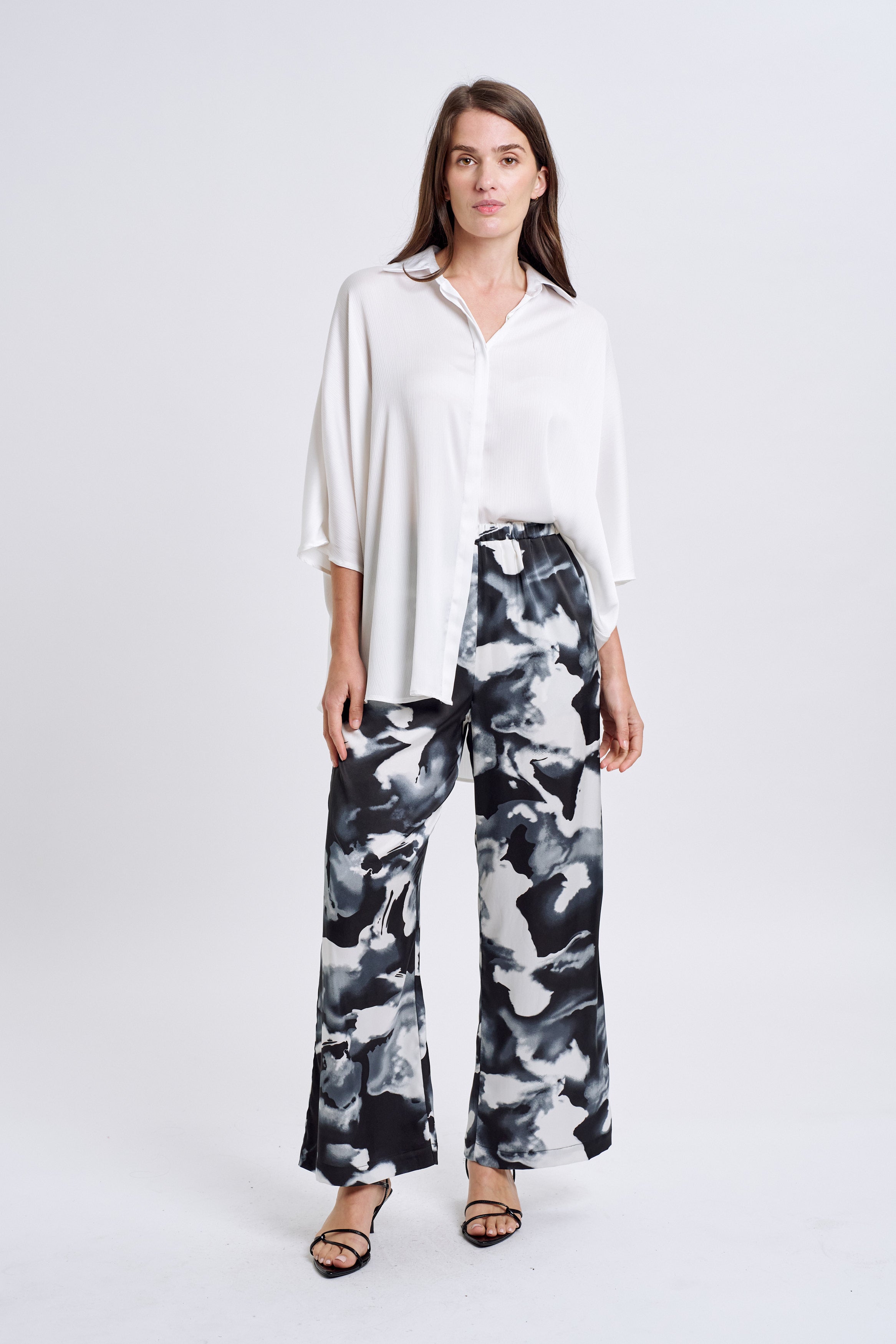 Woman wearing a white shirt and black and white patterned pants on a white background