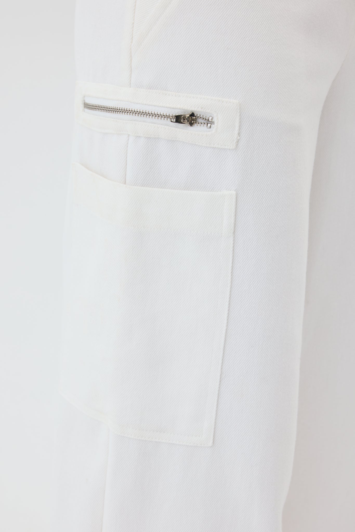 Close-up of a white garment with a zipper pocket on a light gray background