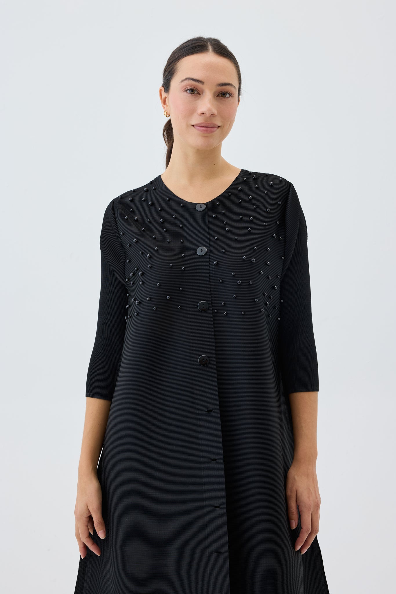 Woman wearing a black dress with bead embellishments on a white background