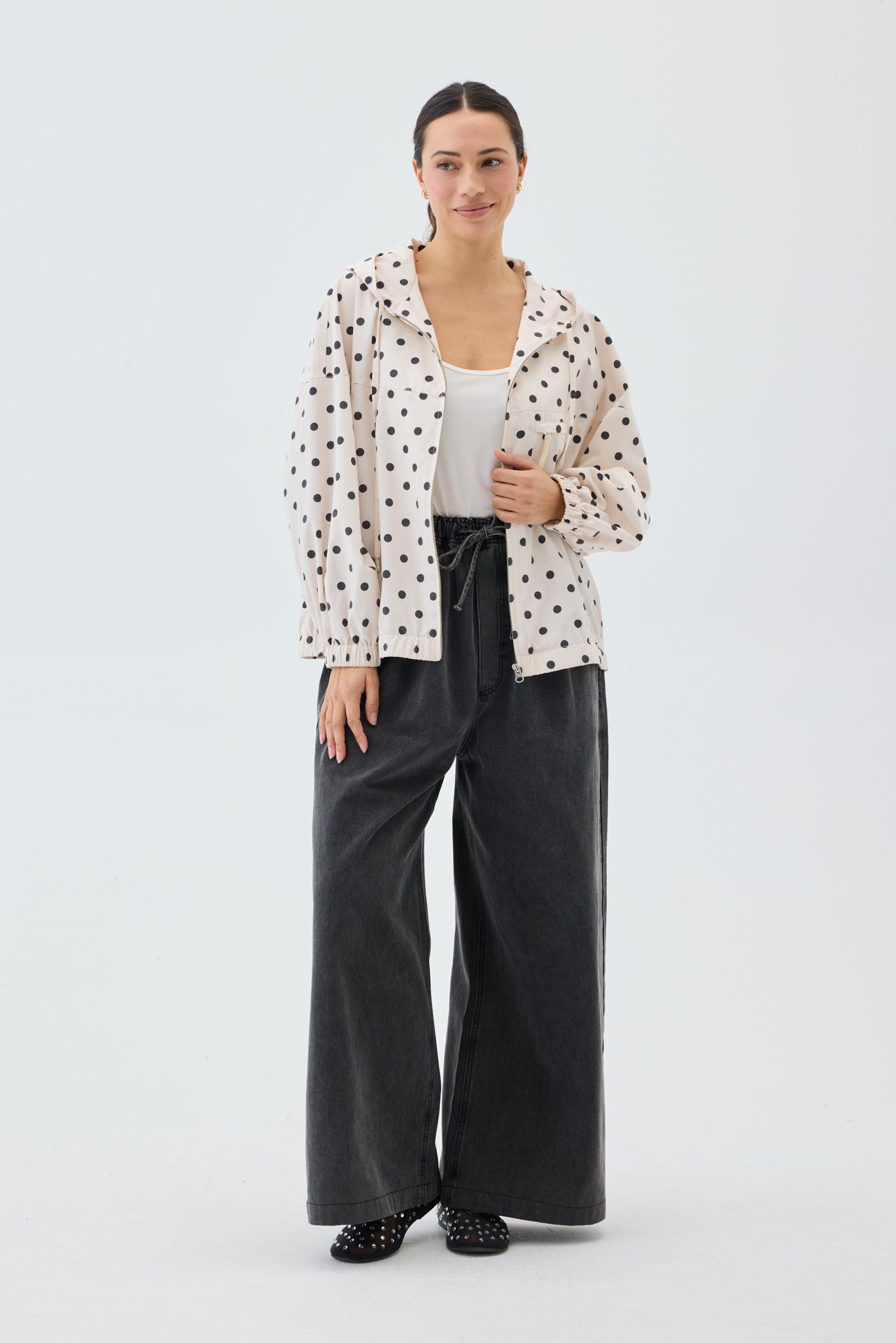 Woman wearing a polka dot blouse and black pants on a white background