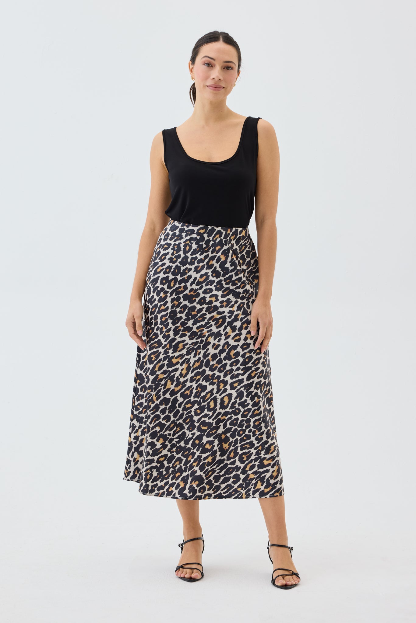 Woman wearing a black tank top and leopard print skirt on a white background