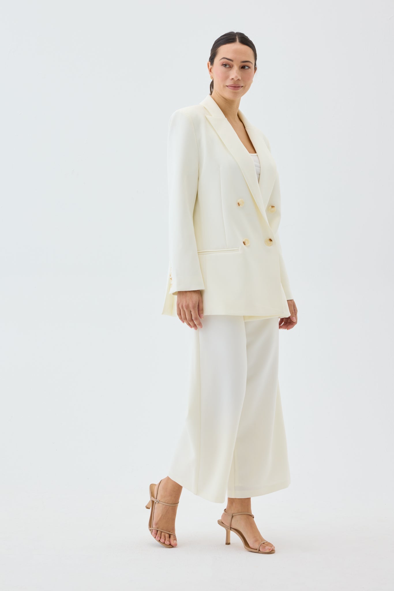 Woman wearing a white blazer and pants on a white background