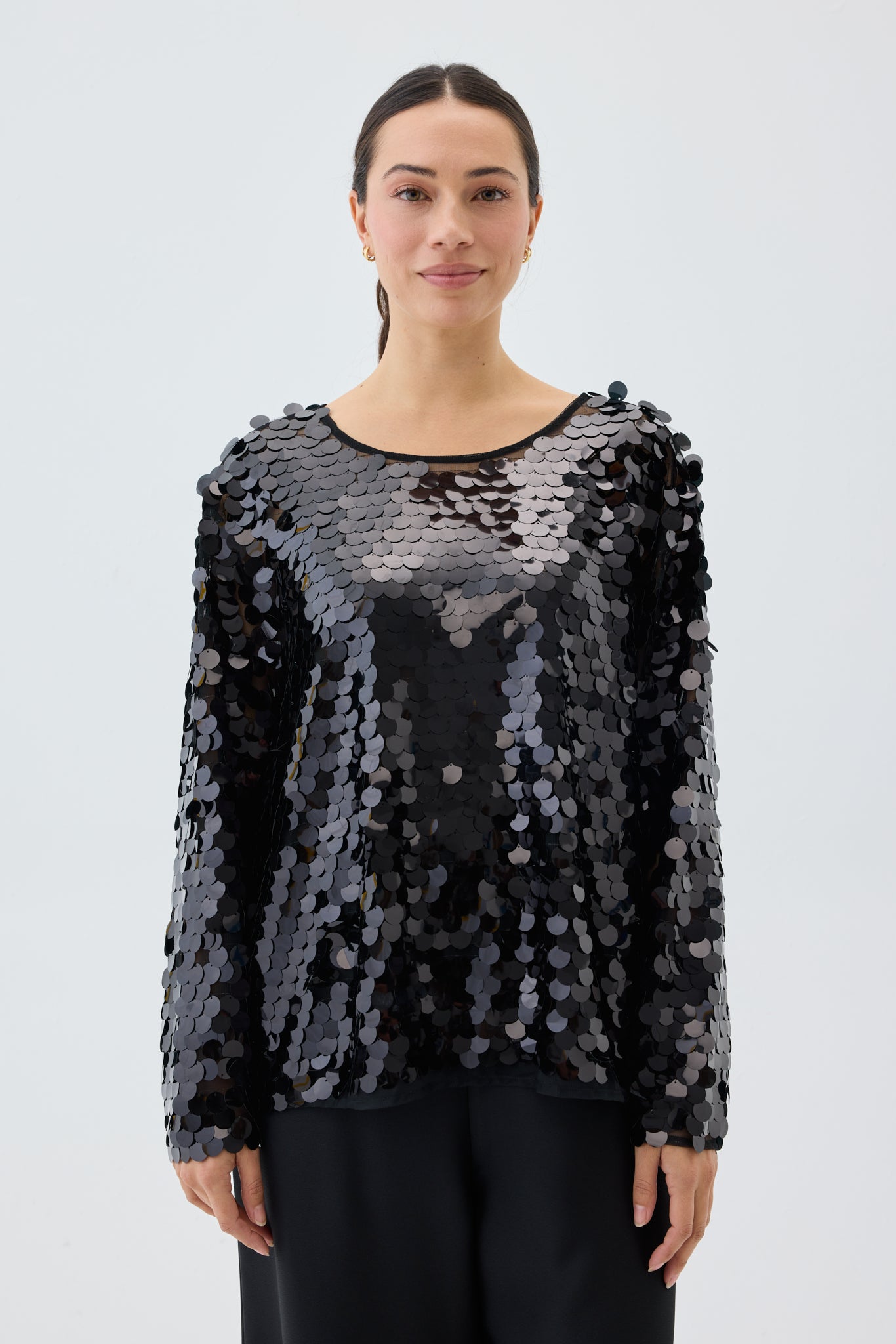 Woman wearing a black sequin top against a white background