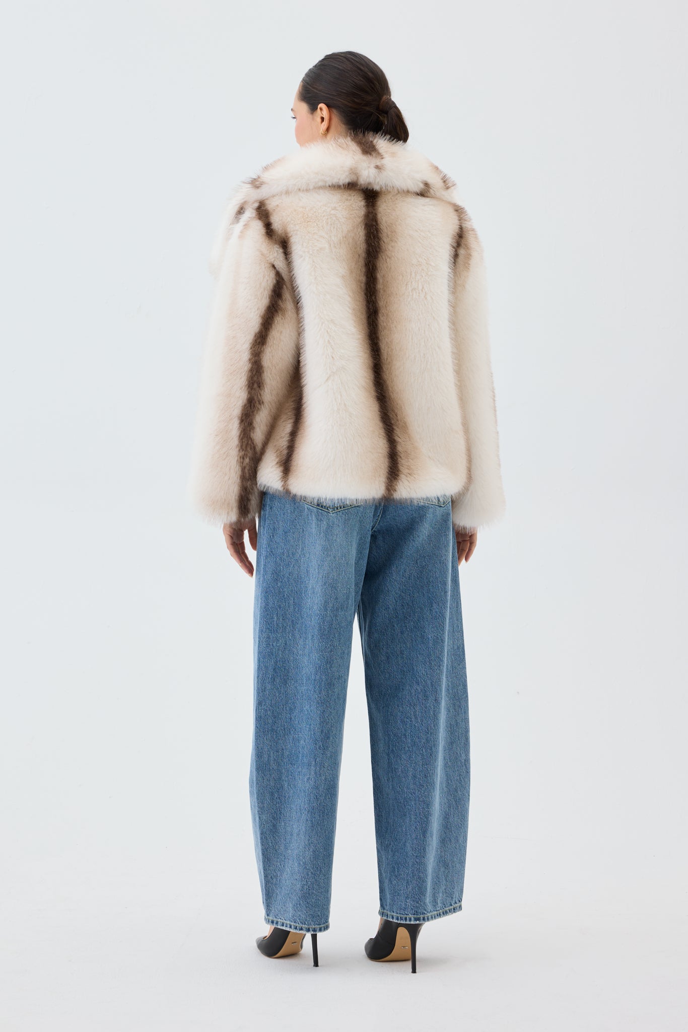 Person wearing a fur coat and jeans on a white background