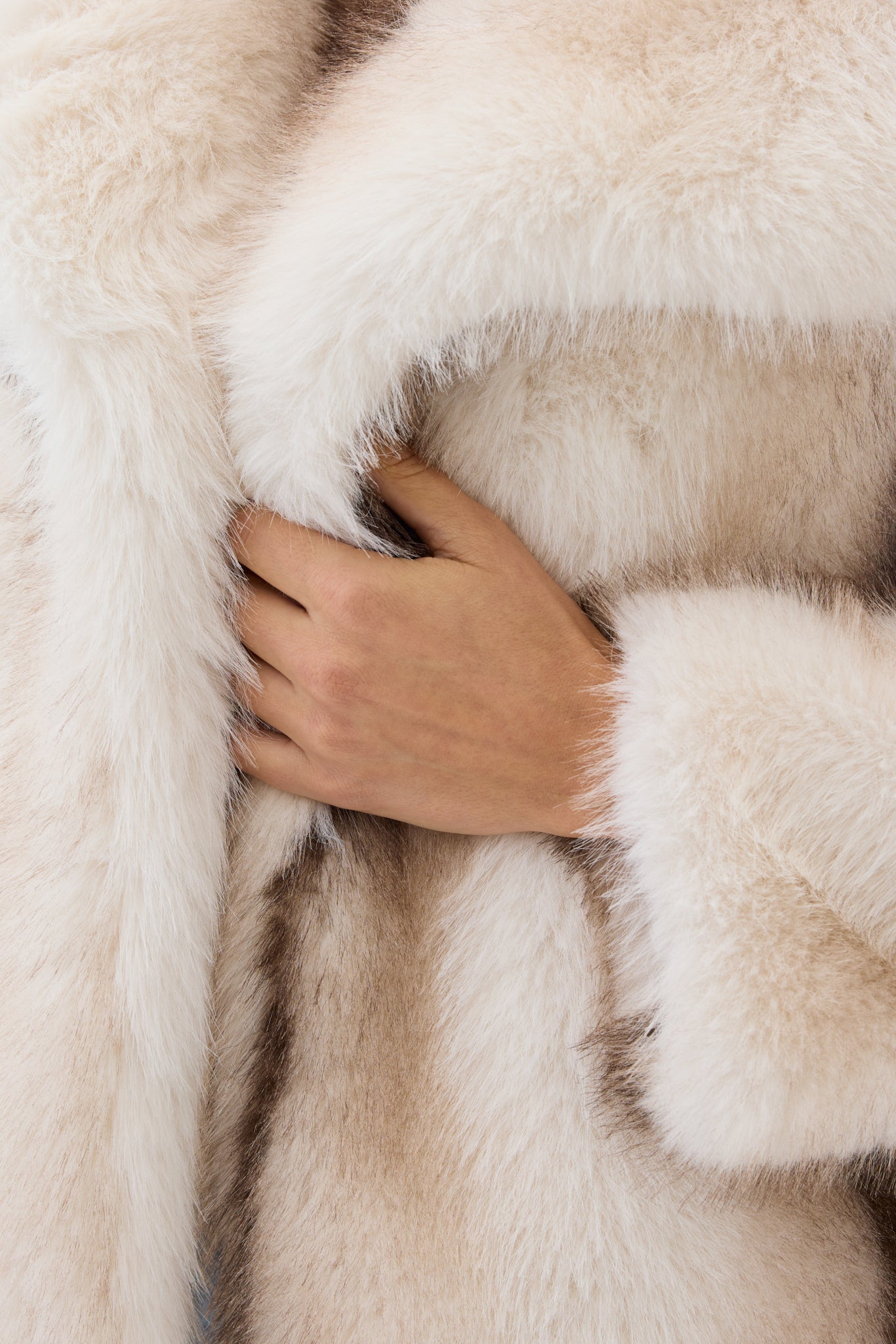 Close-up of a hand holding a piece of fur with a neutral background