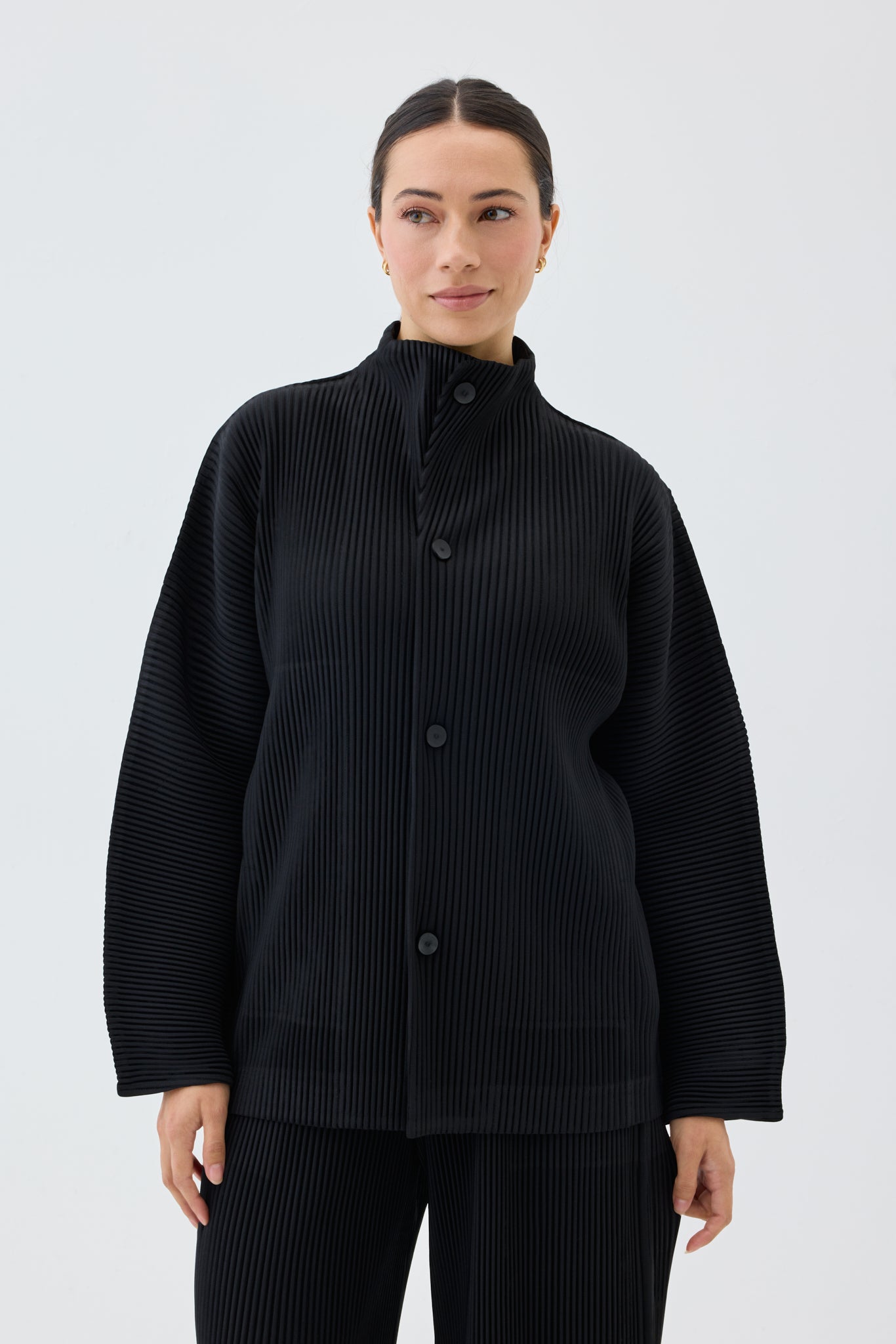 Person wearing a black pleated jacket on a white background