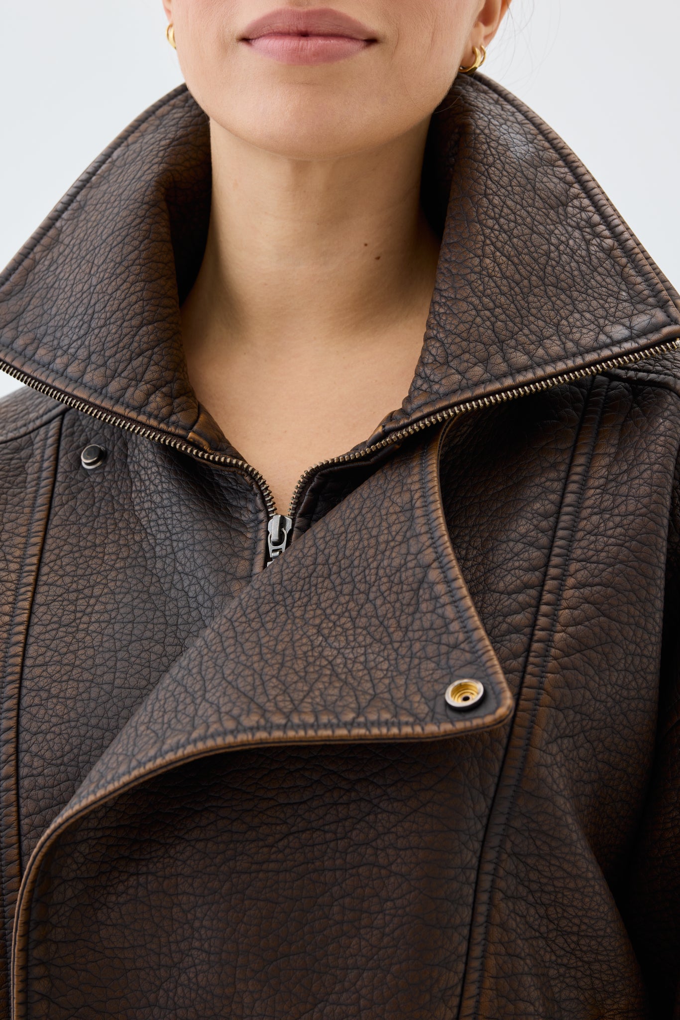 Close-up of a brown leather jacket with a focus on the collar and zipper.